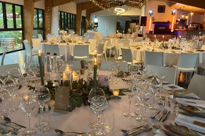 Salle de réception décorée avec des tables rondes, nappes blanches, serviettes orange et chaises blanches.