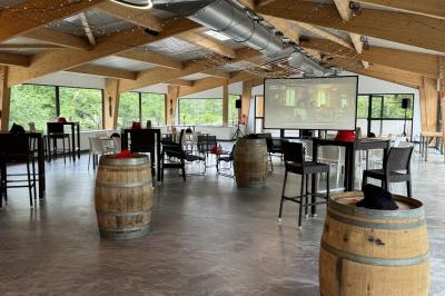 Salle de réception décorée avec des tables rondes, nappes blanches, serviettes orange et chaises blanches.