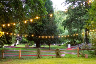 Salle de réception décorée avec des tables rondes, nappes blanches, serviettes orange et chaises blanches.