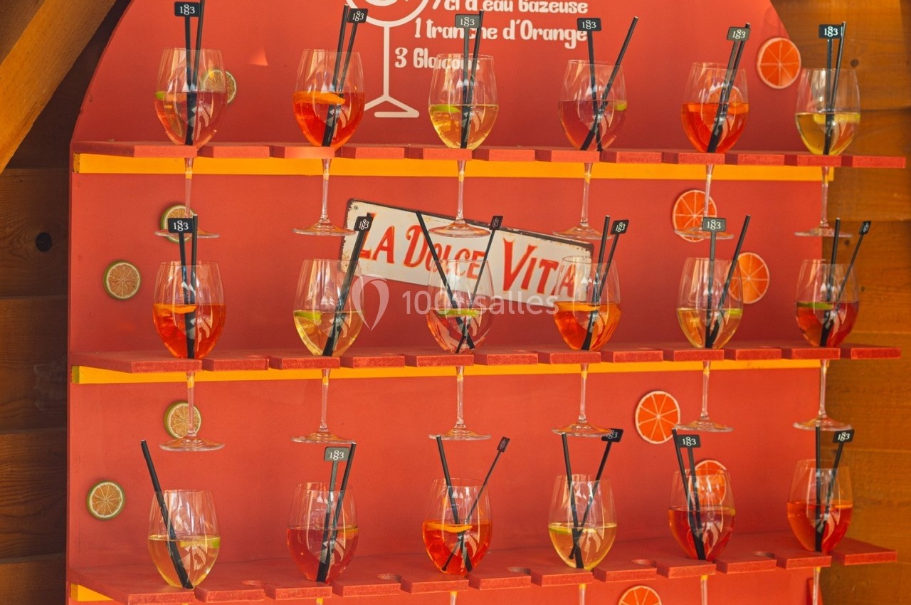 Présentoir rouge avec des verres de Spritz alignés, accompagnés d'une recette inscrite en haut.