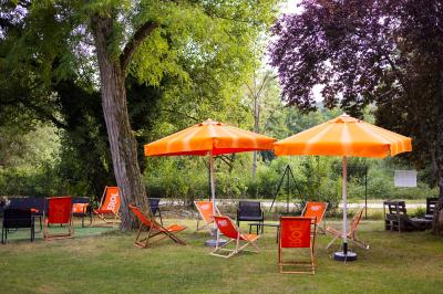 Salle de réception décorée avec des tables rondes, nappes blanches, serviettes orange et chaises blanches.