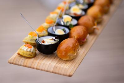 Salle de réception décorée avec des tables rondes, nappes blanches, serviettes orange et chaises blanches.