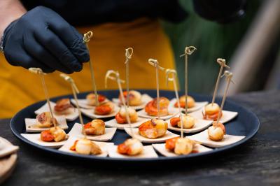 Salle de réception décorée avec des tables rondes, nappes blanches, serviettes orange et chaises blanches.