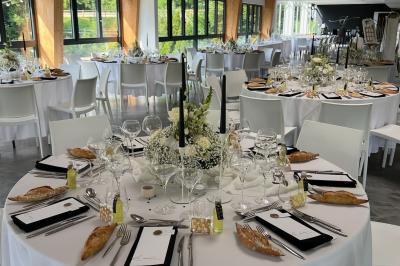 Salle de réception décorée avec des tables rondes, nappes blanches, serviettes orange et chaises blanches.