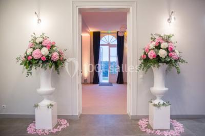 Buffet de petit-déjeuner avec viennoiseries, pain, confiture et grille-pain, devant une fenêtre et des fleurs décoratives.