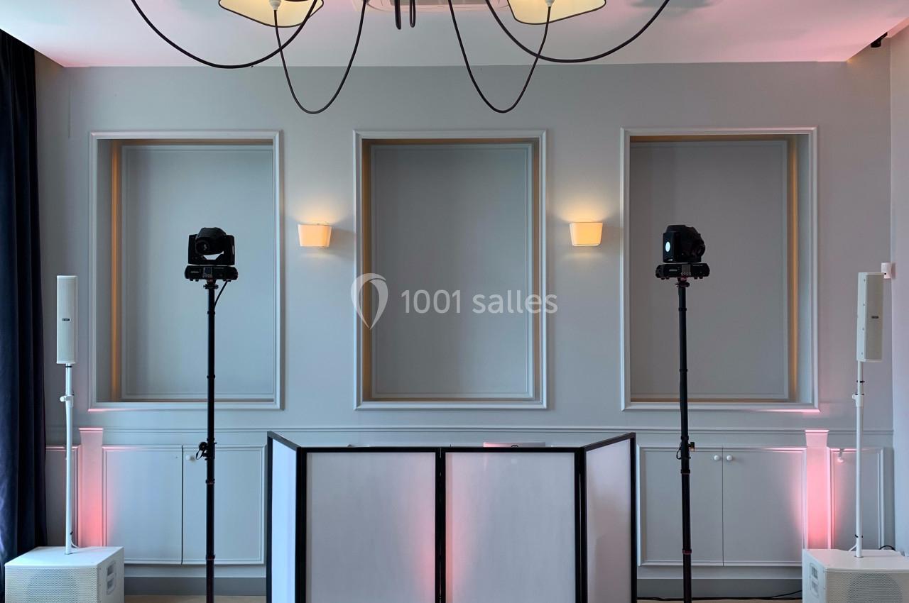 Installation d'équipements audio et d'éclairage avec une table blanche dans une salle lumineuse au design épuré.