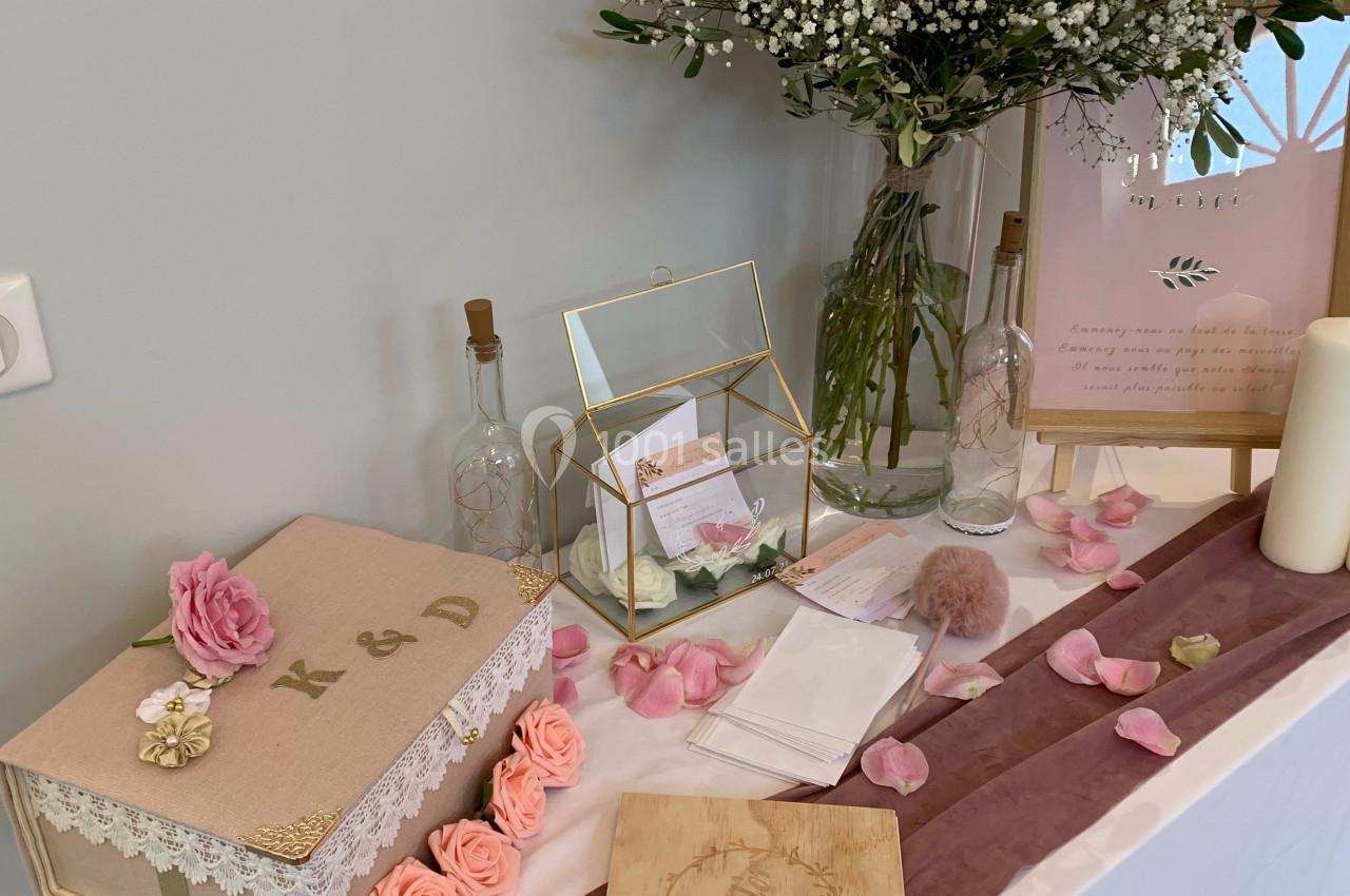 Décoration de table avec boîte personnalisée, fleurs roses et blanches, livre en bois et pétales pour un événement festif.