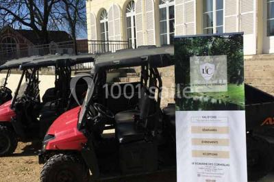 Véhicule tout-terrain rouge stationné sur des marches en pierre devant un bâtiment avec de grandes fenêtres.