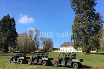 Véhicule tout-terrain rouge stationné sur des marches en pierre devant un bâtiment avec de grandes fenêtres.