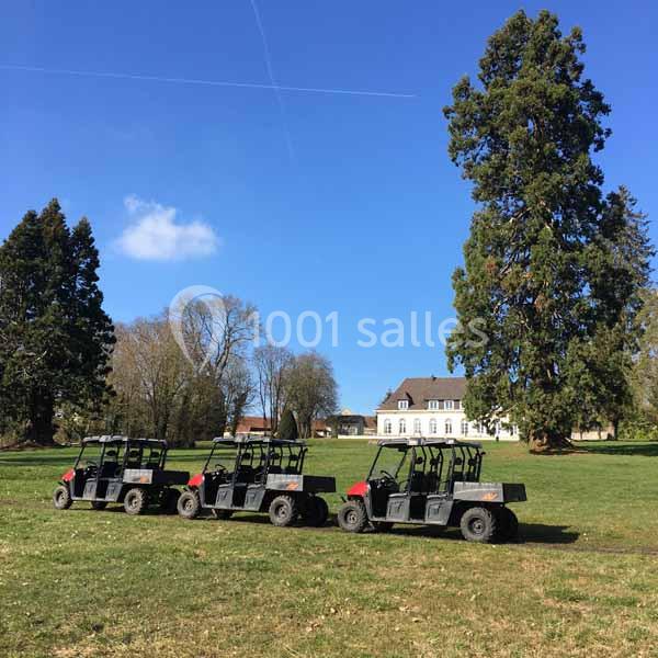 Quatre véhicules tout-terrain alignés sur une pelouse, avec un grand arbre et un bâtiment en arrière-plan.