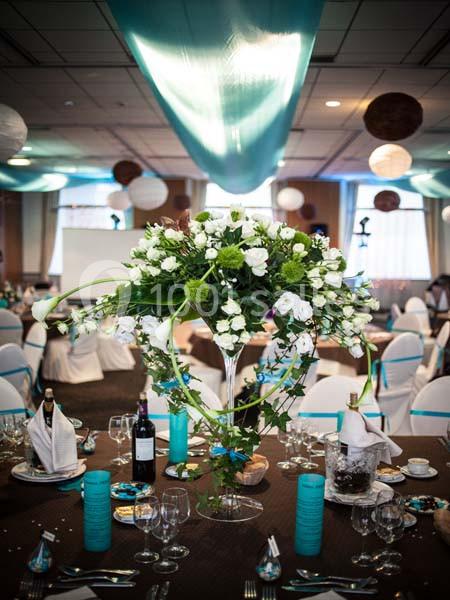Centre de table floral avec des fleurs blanches et vertes dans une salle décorée pour un événement festif.
