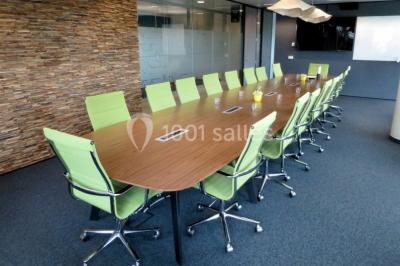 Façade vitrée d'un bâtiment moderne avec une terrasse en bois éclairée par le soleil.