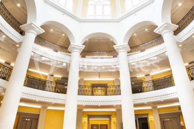Salle de conférence lumineuse avec des rangées de chaises blanches et une table en bois au premier plan.