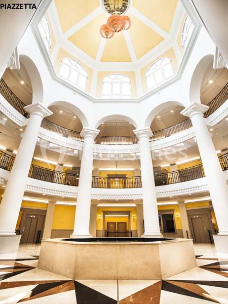 Intérieur d'un bâtiment avec une rotonde lumineuse, colonnes blanches et balustrades en métal noir.