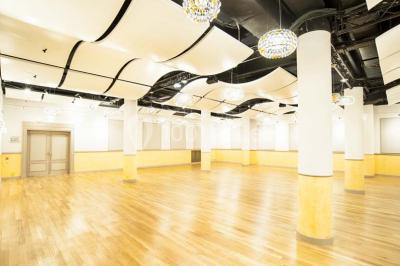 Salle de conférence lumineuse avec des rangées de chaises blanches et une table en bois au premier plan.