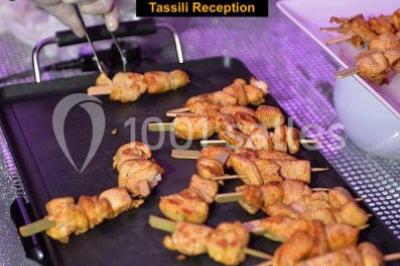 Salle de réception décorée avec des lumières violettes, une arche florale et des chaises transparentes disposées autour de…