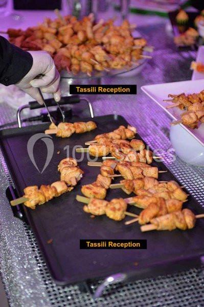 Brochettes de poulet grillées sur une plancha, servies lors d'un buffet.