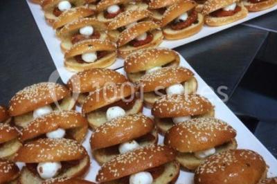 Salle de réception décorée avec des lumières violettes, une arche florale et des chaises transparentes disposées autour de…
