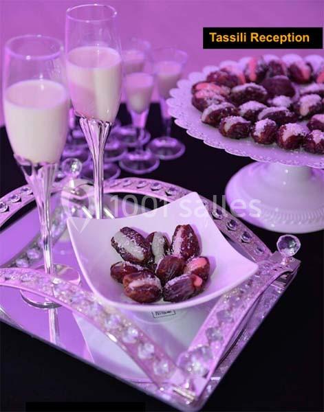 Plateau décoratif avec des dattes farcies dans un bol et des coupes de lait, éclairé par une lumière violette.