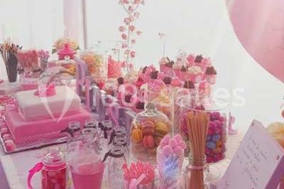 Salle de réception décorée avec des lumières violettes, une arche florale et des chaises transparentes disposées autour de…