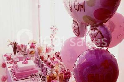 Salle de réception décorée avec des lumières violettes, une arche florale et des chaises transparentes disposées autour de…