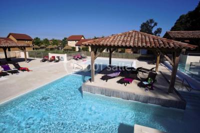 Lit double avec tête de lit décorative, coussins beige et bleu, tables de chevet avec lampes et décoration murale.