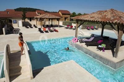 Lit double avec tête de lit décorative, coussins beige et bleu, tables de chevet avec lampes et décoration murale.