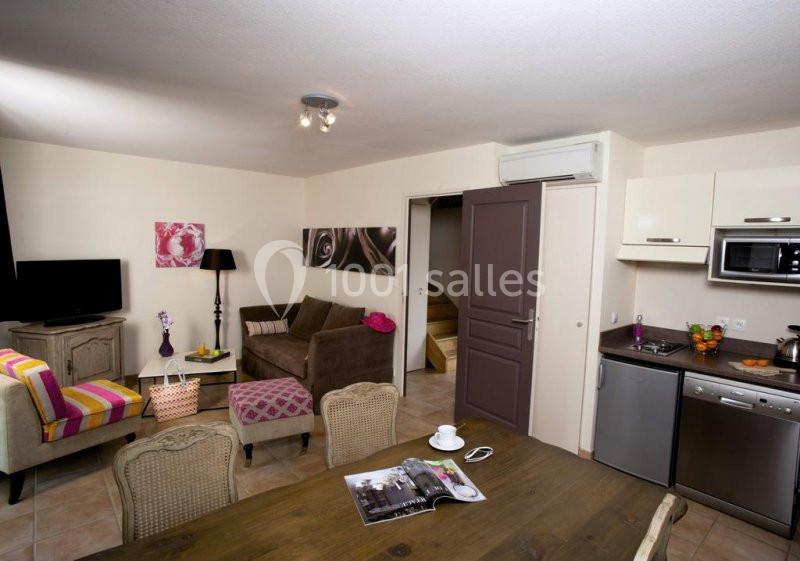 Salon avec canapé, table en bois, cuisine équipée et décoration moderne dans un intérieur lumineux.