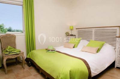 Lit double avec tête de lit décorative, coussins beige et bleu, tables de chevet avec lampes et décoration murale.