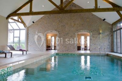 Lit double avec tête de lit décorative, coussins beige et bleu, tables de chevet avec lampes et décoration murale.