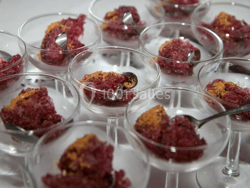 Desserts glacés rouges servis dans des coupes en verre, accompagnés de petites cuillères argentées.