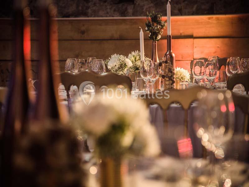 Table décorée pour un événement, avec bougies, fleurs blanches et verres, dans une ambiance chaleureuse et tamisée.