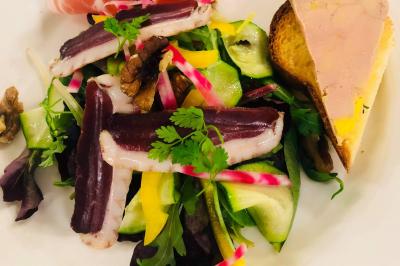 Assiette composée de salade verte, magret de canard fumé, légumes croquants, foie gras sur toast et tranche de jambon.