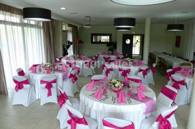 Allée avec tapis rouge menant à une arche décorée de fleurs, dans un espace extérieur ensoleillé.