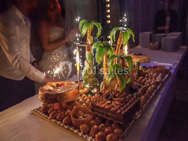 Dessert de fête avec pièces montées, gâteaux décorés de palmiers et bougies étincelantes sur une table éclairée.