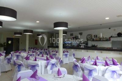 Allée avec tapis rouge menant à une arche décorée de fleurs, dans un espace extérieur ensoleillé.