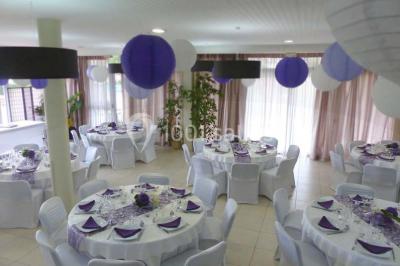Allée avec tapis rouge menant à une arche décorée de fleurs, dans un espace extérieur ensoleillé.
