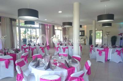 Allée avec tapis rouge menant à une arche décorée de fleurs, dans un espace extérieur ensoleillé.