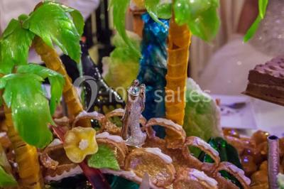 Allée avec tapis rouge menant à une arche décorée de fleurs, dans un espace extérieur ensoleillé.