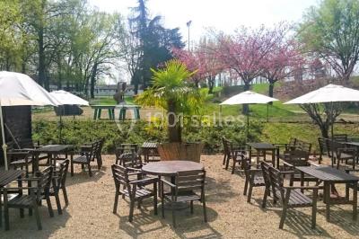 Allée avec tapis rouge menant à une arche décorée de fleurs, dans un espace extérieur ensoleillé.