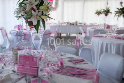 Allée avec tapis rouge menant à une arche décorée de fleurs, dans un espace extérieur ensoleillé.