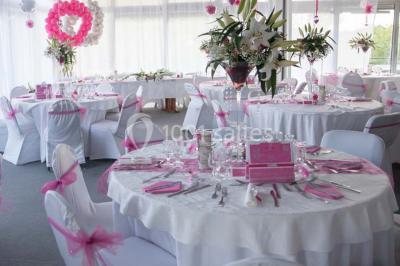 Allée avec tapis rouge menant à une arche décorée de fleurs, dans un espace extérieur ensoleillé.