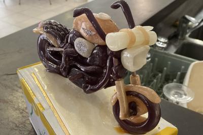 Allée avec tapis rouge menant à une arche décorée de fleurs, dans un espace extérieur ensoleillé.