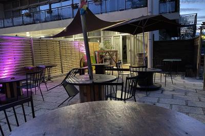 Allée avec tapis rouge menant à une arche décorée de fleurs, dans un espace extérieur ensoleillé.