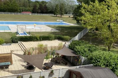 Allée avec tapis rouge menant à une arche décorée de fleurs, dans un espace extérieur ensoleillé.