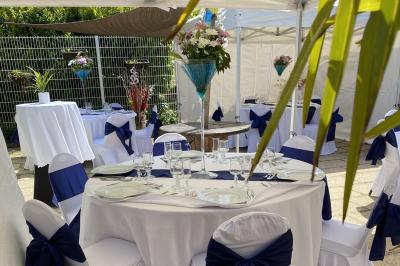Allée avec tapis rouge menant à une arche décorée de fleurs, dans un espace extérieur ensoleillé.