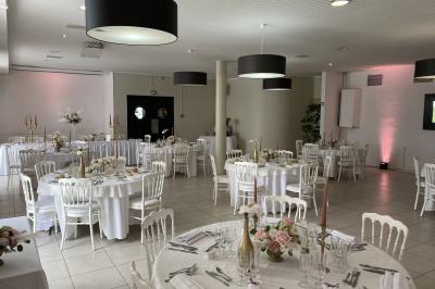 Allée avec tapis rouge menant à une arche décorée de fleurs, dans un espace extérieur ensoleillé.