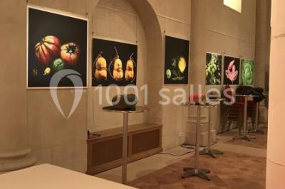 Salle avec des chaises rouges alignées, une table avec des micros, un écran de projection et des bannières promotionnelles.