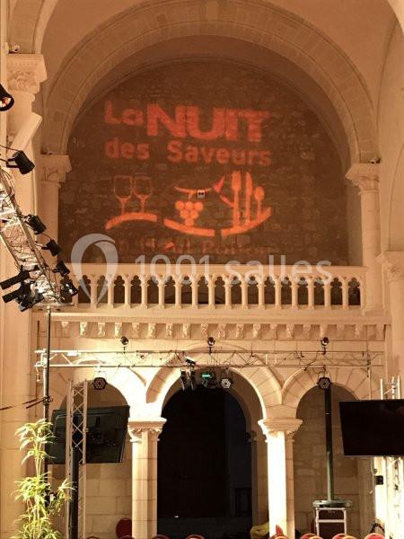 Projection lumineuse ’La Nuit des Saveurs’ sur un mur en pierre dans une salle voûtée avec arches et éclairages.