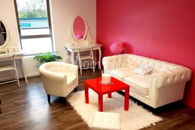 Salle de jeux lumineuse avec une cabane en tissu, un tapis de chiffres, une cuisine pour enfants et des tables colorées.